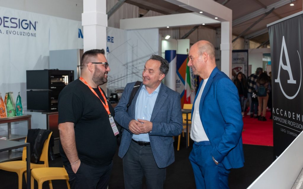 Tre visitatori conversano nel padiglione della fiera