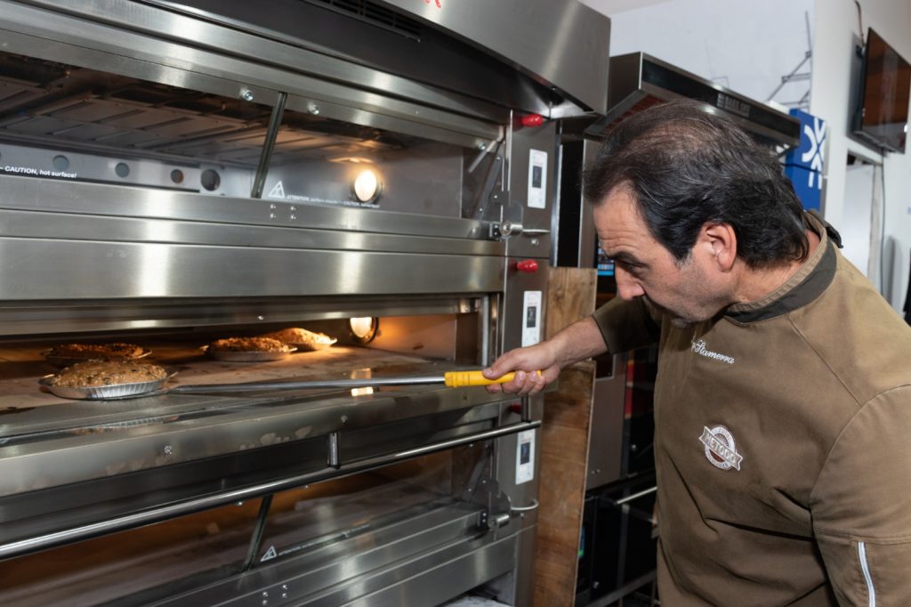 Un fornaio inforna una teglia in un forno a piani