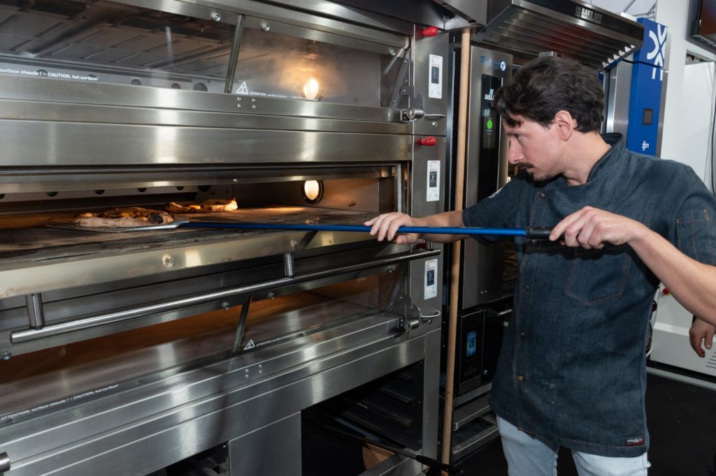 Un fornaio inforna con la pala in un forno a piani Pavailler