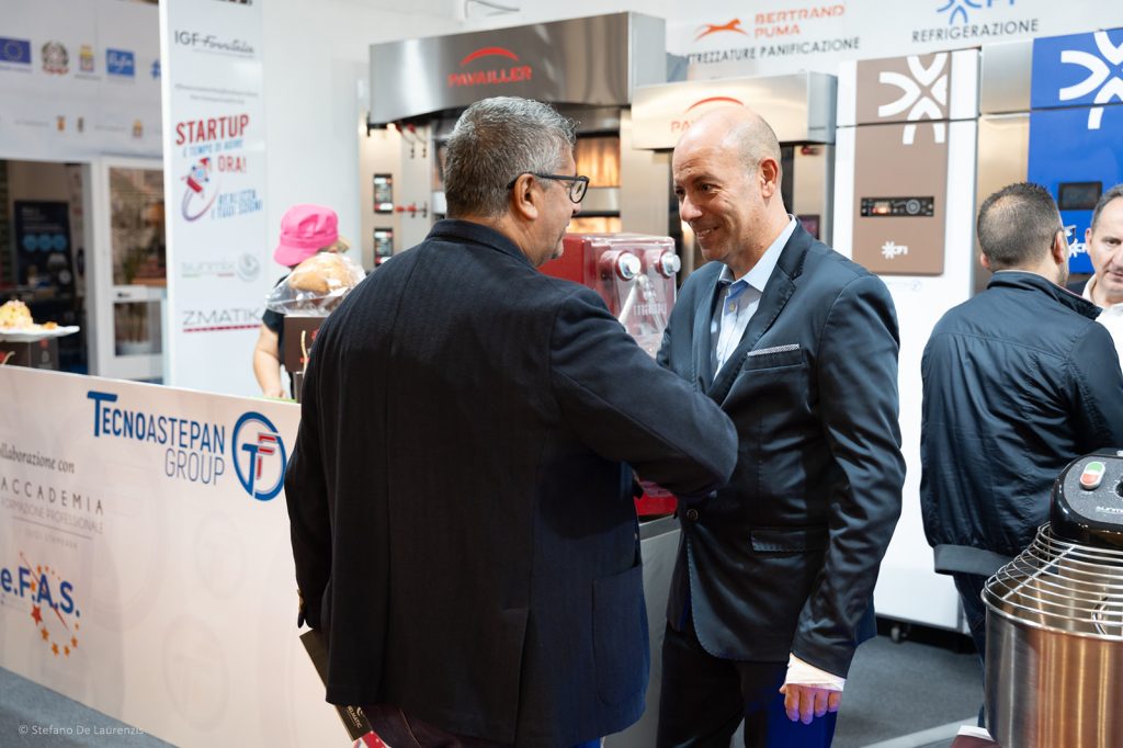 Due visitatori in giacca conversano allo stand Tecnoastepan Group